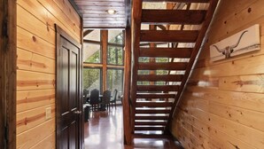 Interior de madera con una escalera, paredes de madera y techo con vigas a la vista.