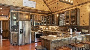 Cocina amplia con armarios de madera, electrodomésticos de acero inoxidable y encimera de granito.