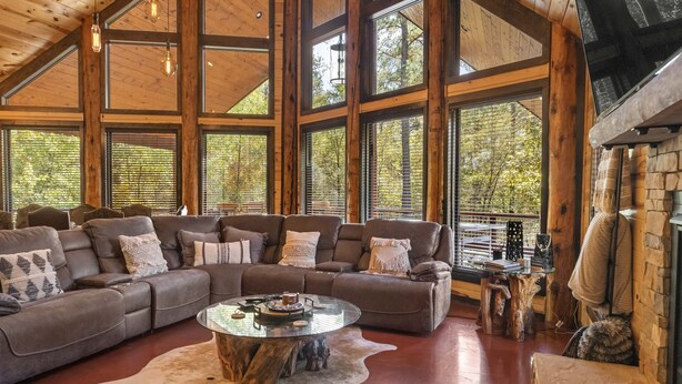 Un salón amplio con un sofá modular grande, una mesa de centro de vidrio y una chimenea de piedra.