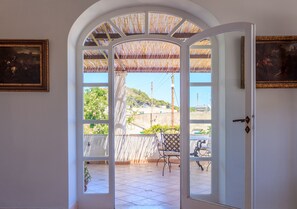 Ein Durchgang zu einem Balkon mit Blick auf eine Hügellandschaft und Stromleitungen.