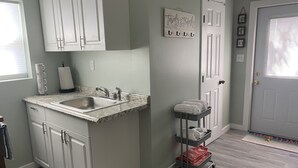 A kitchen with a sink, cabinets, a countertop, and a towel rack. - Banana Beach Cottage (Lake Worth)