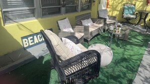Ein Patio mit Korbmöbeln, einem kleinen runden Tisch und einem Schild mit der Aufschrift 'BEACH'.