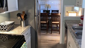 Eine Küche mit Kühlschrank, Herd, Mikrowelle und einem Essbereich mit Tisch und Stühlen.