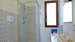A bathroom with a glass-enclosed shower, a toilet, and a sink with a glass basin.