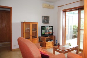 Una sala de estar con televisor, mueble de madera y un sofá.
