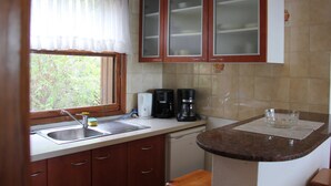 Une petite cuisine équipée d’un évier, d’une machine à café et de placards.