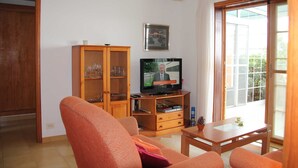 Un salon équipé d’un téléviseur, d’un meuble en bois et d’une porte-fenêtre coulissante.