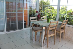 A dining area with a glass table and chairs, large windows with a view of greenery, and a sliding glass door. - La Palma - Jardin de Aridane (El Paso)