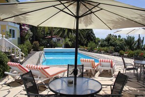 A poolside area with lounge chairs, a table, and an umbrella. - La Gomera - Jardin de Aridane (El Paso)