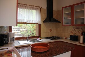 Una cocina con ventana, estufa, pileta y alacenas.