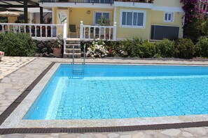 A rectangular swimming pool with a white border and a metal ladder leading into it.