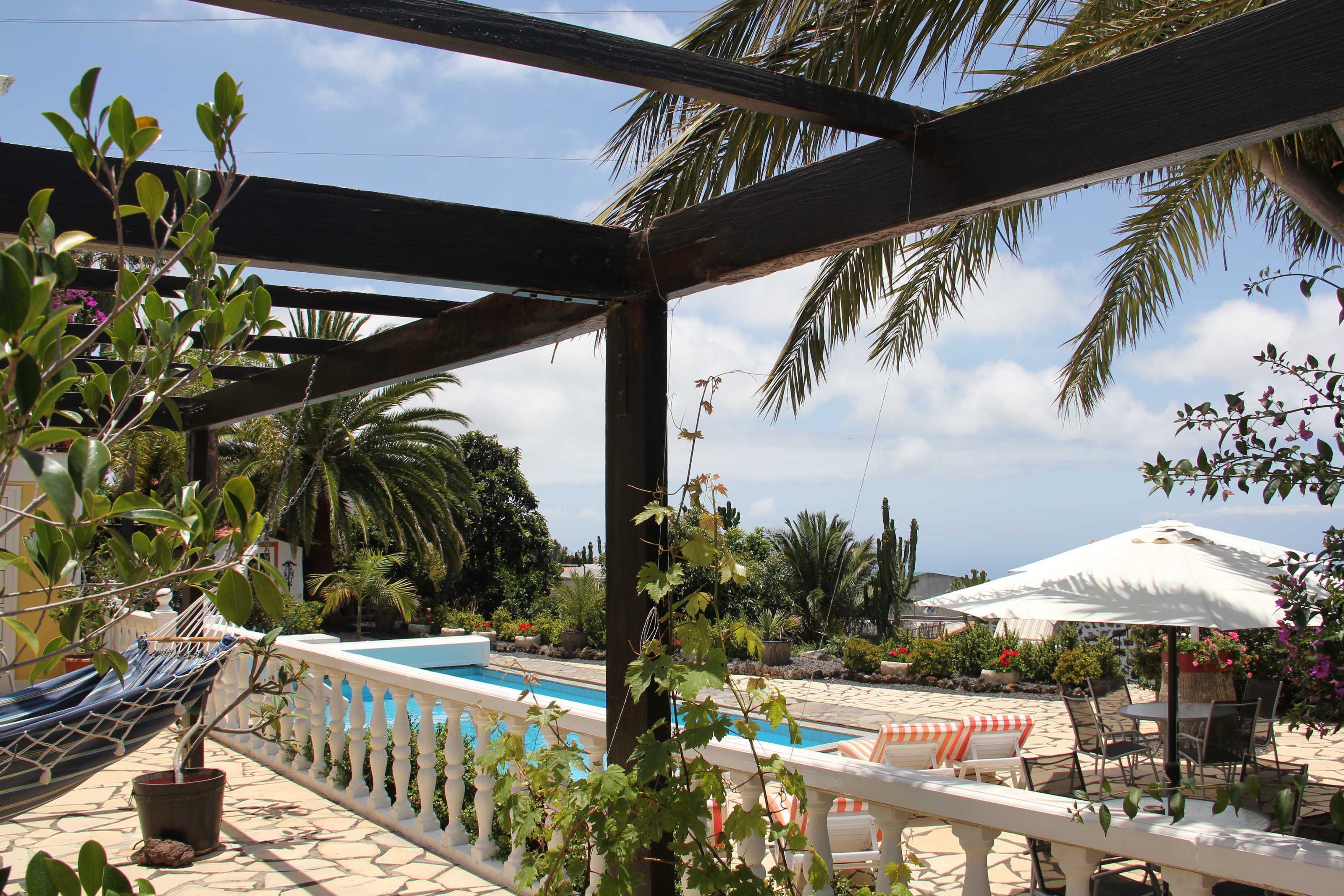 Un espace piscine agrémenté d’une pergola, de chaises longues et de parasols.