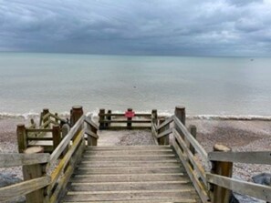 A wooden staircase leading to a beach with a cloudy sky.