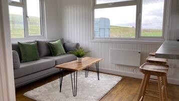 Een moderne woonkamer met een grijze bank, een houten salontafel en een wit vloerkleed.