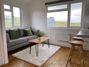 Een moderne woonkamer met een grijze bank, een houten salontafel en een wit vloerkleed.