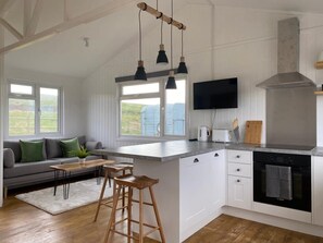 Una cocina moderna con una isla grande, horno empotrado y televisor sobre la encimera.