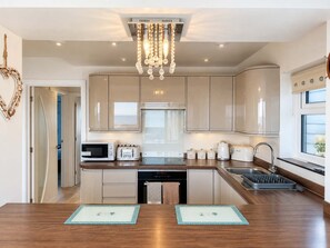 A modern kitchen with a central island, stainless steel appliances, and a decorative chandelier.