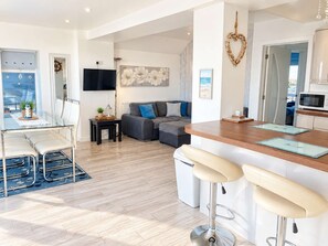 A modern living area with a sofa, a dining table, and a kitchen area with a microwave.