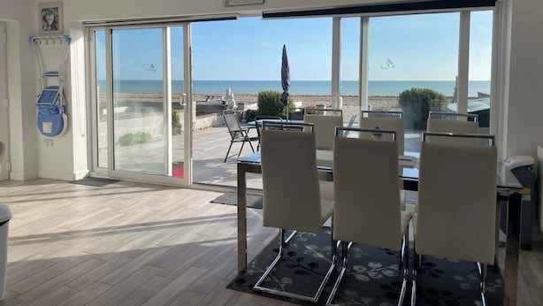 A dining area with a view of the beach, a wheelchair, and a sign reading "Life better at the beach".