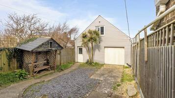 Il s’agit d’une propriété résidentielle dotée d’un garage, d’un abri de jardin en bois, d’une allée gravillonnée et d’une cour clôturée.
