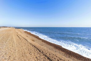 A beach with a clear sky, a sandy shore, and the ocean.