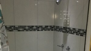 Ducha con puerta de cristal, inodoro y lavabo.