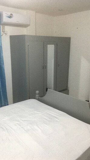 A room with a bed, a wardrobe, and a mirror. - Gated community apt in residential area  (Georgetown)