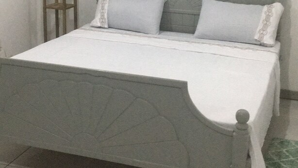 Una cama con cabecera, una mesita de noche y un aire acondicionado de pared.