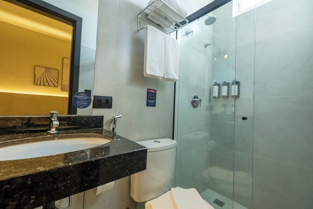 Un baño moderno con lavamanos de mármol, cabina de ducha de vidrio y un inodoro.