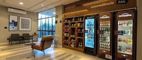 A hotel lobby with seating, vending machines, and a view of the outdoors.