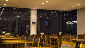 Ravintola, jossa on puupöydät ja -tuolit, suuret ikkunat ja moderni sisustus.