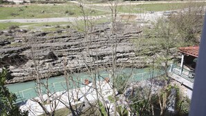 Un paisaje rocoso con un río, un puente y un edificio de techo rojo.