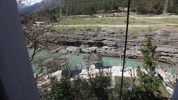 Vista de un río con terreno rocoso y una cancha de tenis al frente.