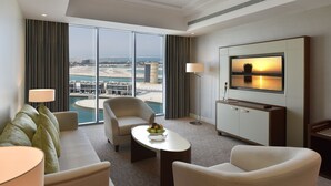 Una habitación de hotel con un ventanal grande, un sofá, una mesita de centro, un televisor y una lámpara.
