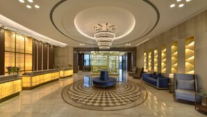 A spacious lobby with a central seating area, a reception desk, and a decorative chandelier. - Aqua Vista Bahrain (Manama)