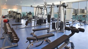 Un gimnasio con varios equipos de ejercicio, incluyendo mancuernas, bancos y máquinas de cardio.