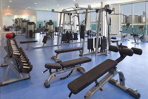 Un gimnasio con varios equipos de ejercicio, incluyendo mancuernas, bancos y máquinas de cardio.