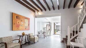 A spacious living area with a dining table, two sofas, and a staircase. - Casa Bugera, Beautiful restored house in Pollensa (Pollença)