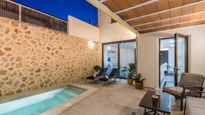 A pool area with stone walls, lounge chairs, and a table. - Casa Bugera, Beautiful restored house in Pollensa (Pollença)