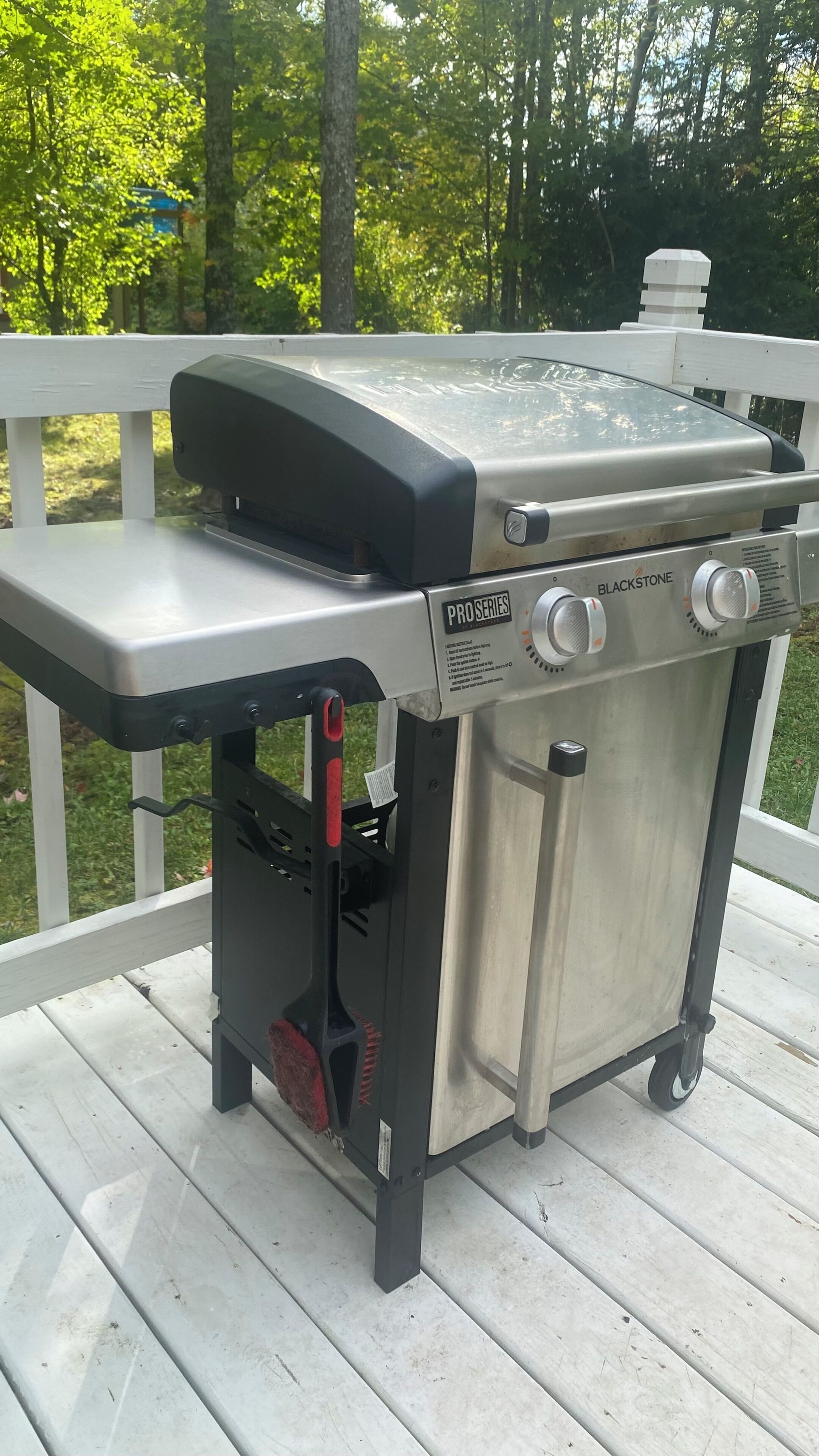 En rustfri stål Blackstone Pro Series grill med et sidebord, placeret på en træterrasse.