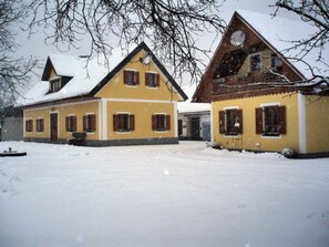 Een geel gebouw met twee verdiepingen, meerdere ramen en een sneeuwbedekte dak.