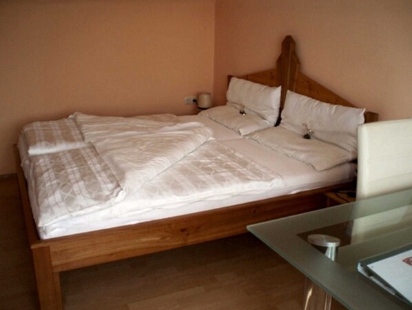 A bed with a wooden headboard, a bedside table, and a nightstand with a lamp.