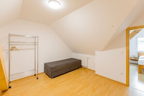 Een kamer met een stapelbed, een metalen droogrek en een houten vloer.