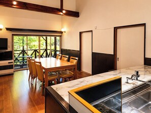 Una cocina moderna con encimera de mármol, pileta integrada y comedor con mesa y sillas de madera.