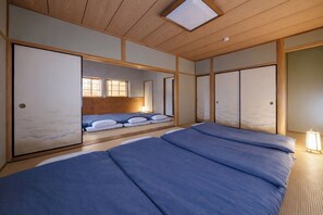 Quarto em estilo japonês tradicional, com tatames, portas deslizantes e teto baixo com claraboia.