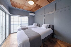 Ein Hotelzimmer mit zwei Betten, einem großen Fenster und einer Holzbalkendecke.