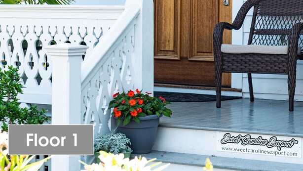 A wooden front door with the number 724, a wicker chair, and a potted plant on the porch. - Sweet Caroline Historic Seaport Key West Home Rental Floor 1 (Key West)
