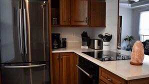 A modern kitchen with stainless steel appliances, wooden cabinets, and a granite countertop. - Sweet Caroline Historic Seaport Key West Home Rental Floor 1 (Key West)
