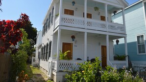 A two-story white house with a balcony, a front door, and a mailbox. - Sweet Caroline Historic Seaport Key West Home Rental Floor 1 (Key West)