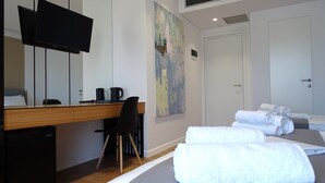 Ein Hotelzimmer mit einem Bett, einem Schreibtisch mit Stuhl, einem Fernseher und einem Bild an der Wand.